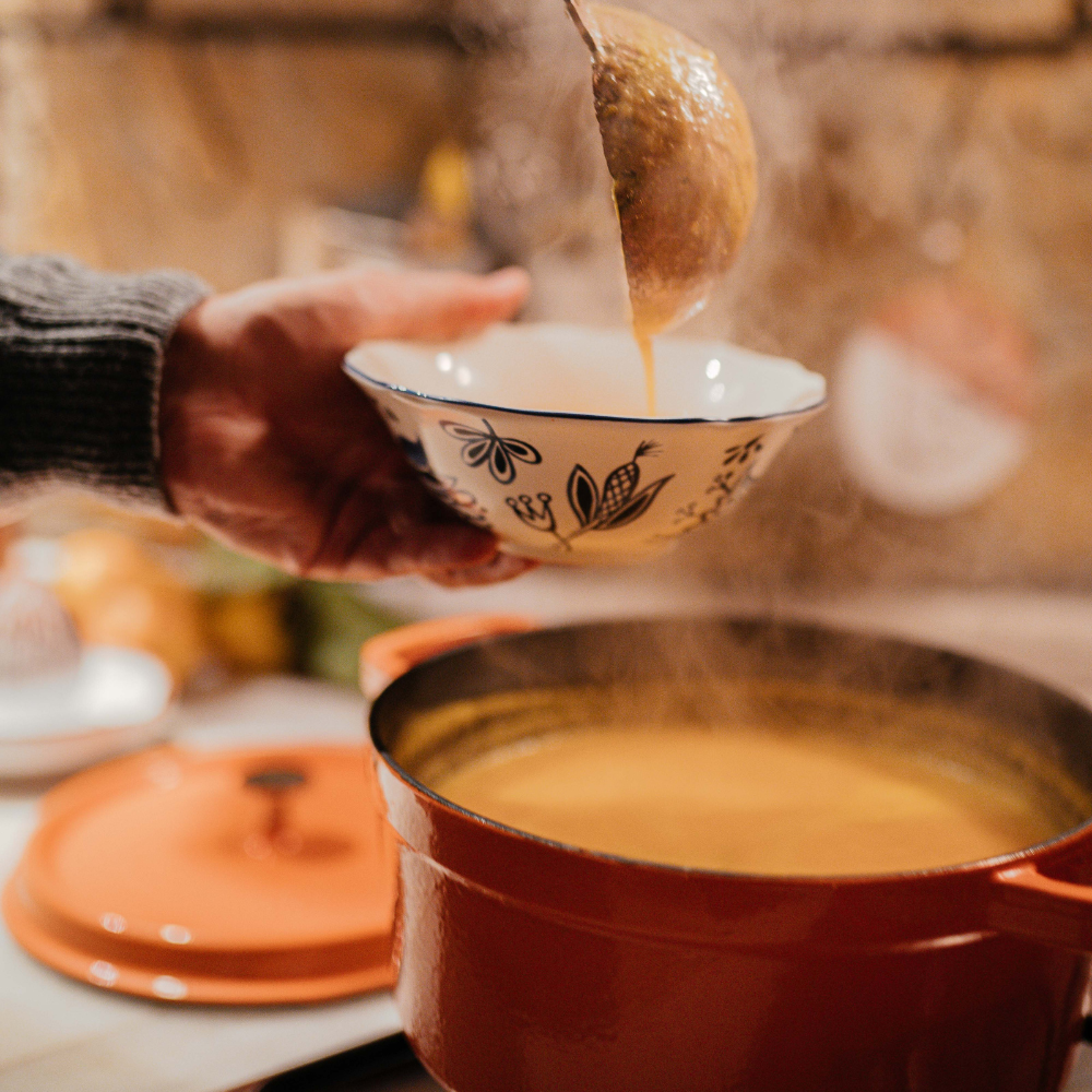 Serving carrot ginger soup topped with crushed pistachios and a drizzle of olive oil