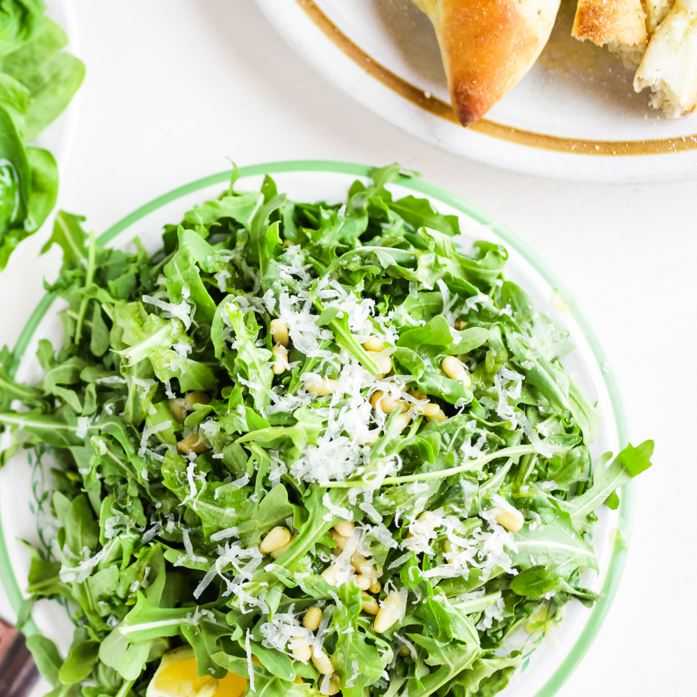 Close-up of a simple arugula salad with tiny toasted croutons and grated pecorino cheese.