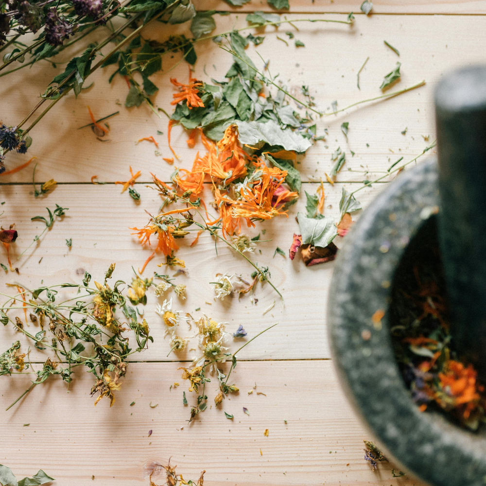 Preparing a homemade herbal tea blend with dried flowers and herbs.
