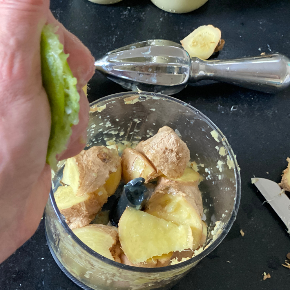 Straining blended ginger shots through a fine mesh sieve for a smooth texture