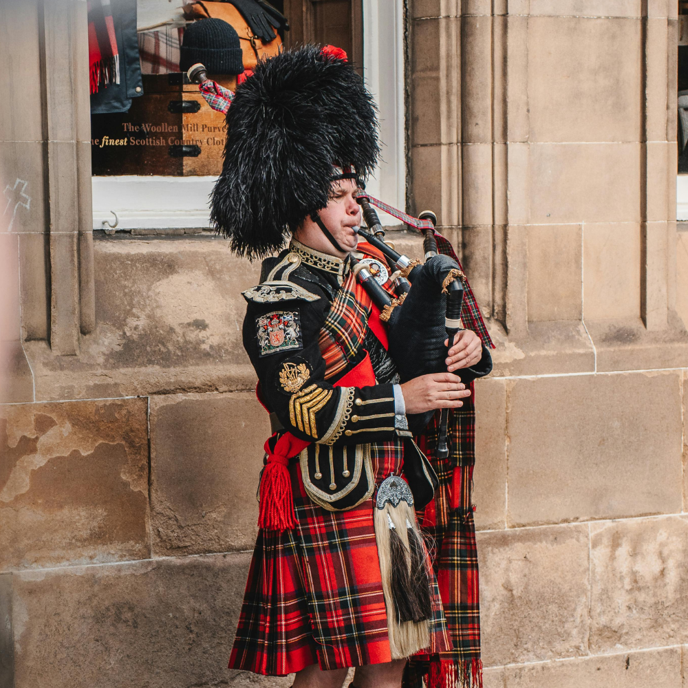 Man performing traditional Scottish music on the bagpipes in Edinburgh, Scotland.