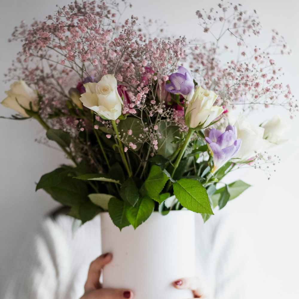 DIY flower arrangement with roses, greenery, and tulips in a glass vase for a handmade Mother’s Day gift