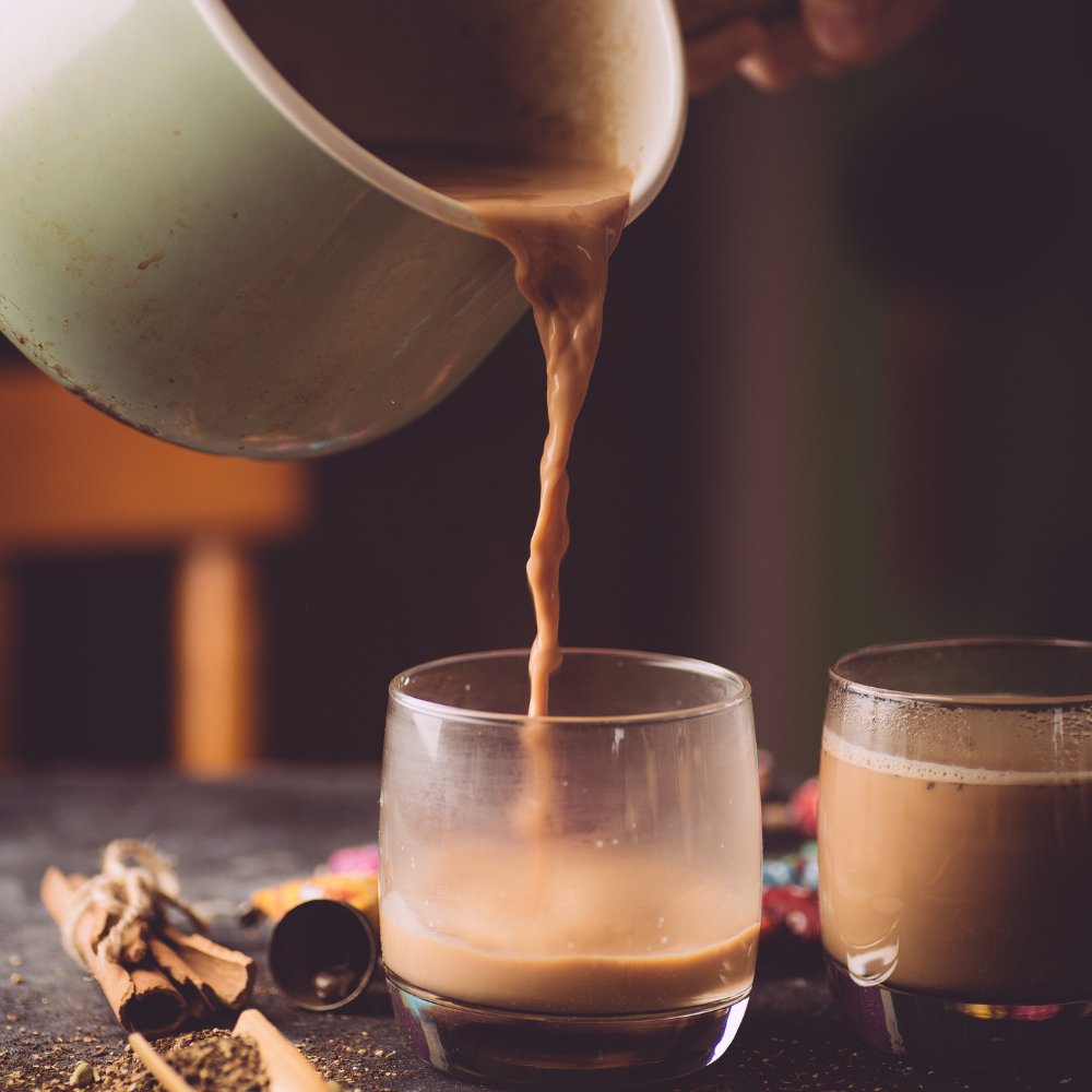 Chai tea brewing with black tea and whole spices including cinnamon, cardamom, cloves, and star anise.