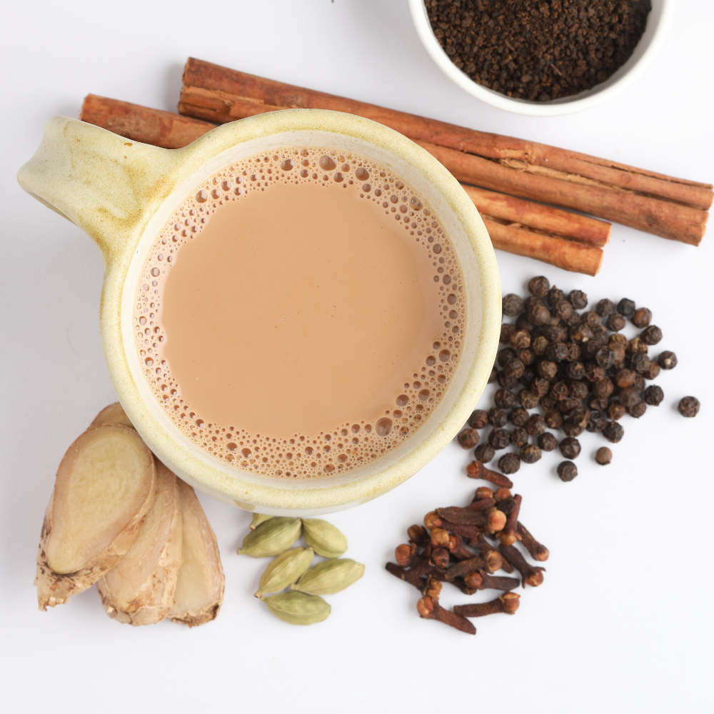 Ingredients for making a chai latte, including black tea, cinnamon, cardamom, cloves, ginger, milk, and honey.