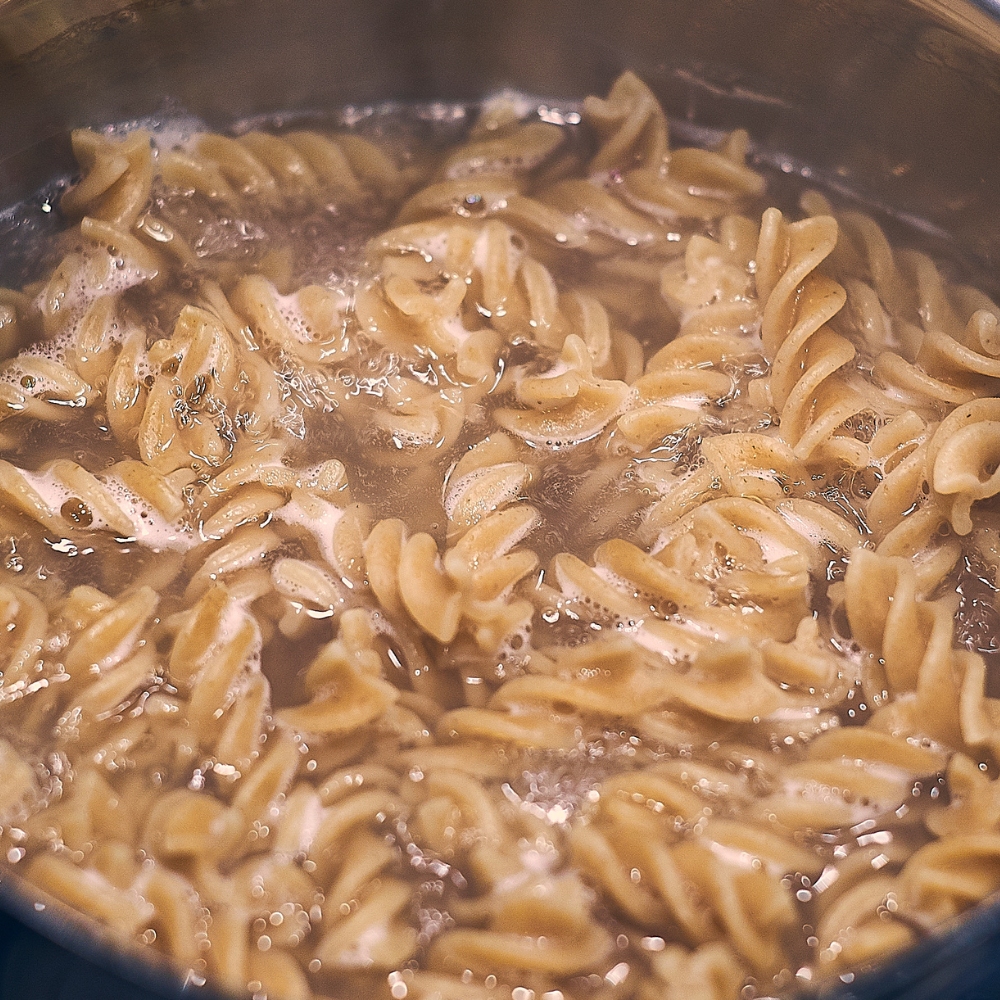 Pasta boiling in salted water in a pot, preparing for tuna pasta salad recipe.