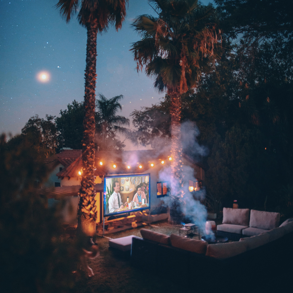 ackyard movie picnic with blankets, pillows, string lights, and snacks for a romantic evening