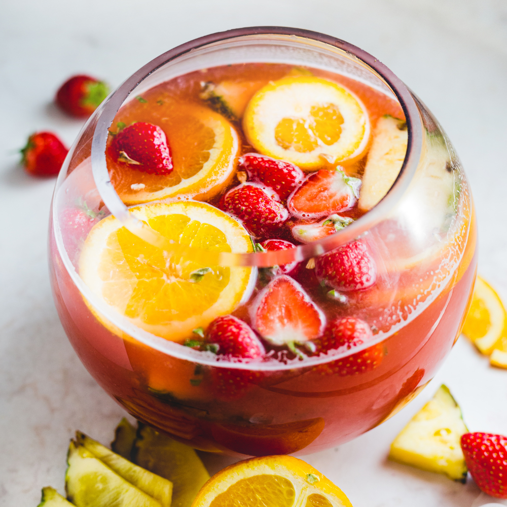 Festive Christmas punch in a glass punch bowl with oranges, limes, and fresh cranberries