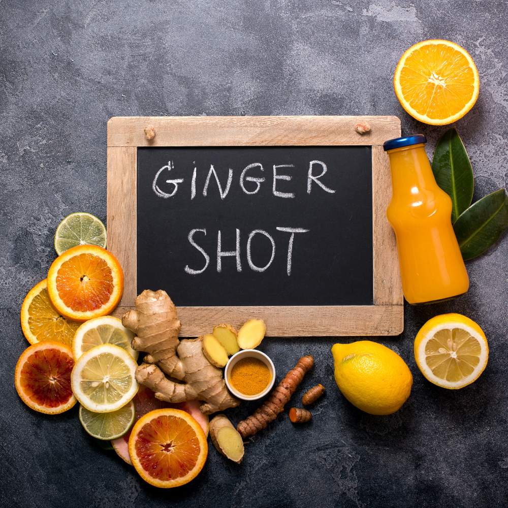 Fresh ingredients for ginger shots including ginger root, lemon, green apple, turmeric, and cayenne