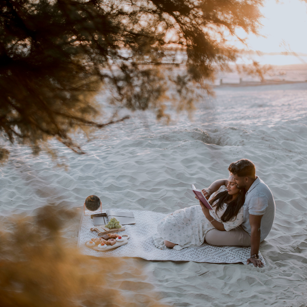 Classic beach picnic for couples with pizzas, hot dogs, fruit, and summer drinks on the sand