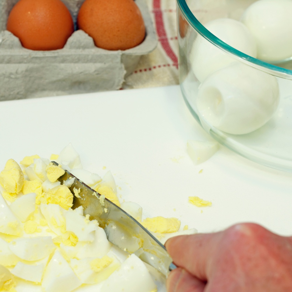 Soft-boiled eggs being cut into cubes for homemade egg salad.