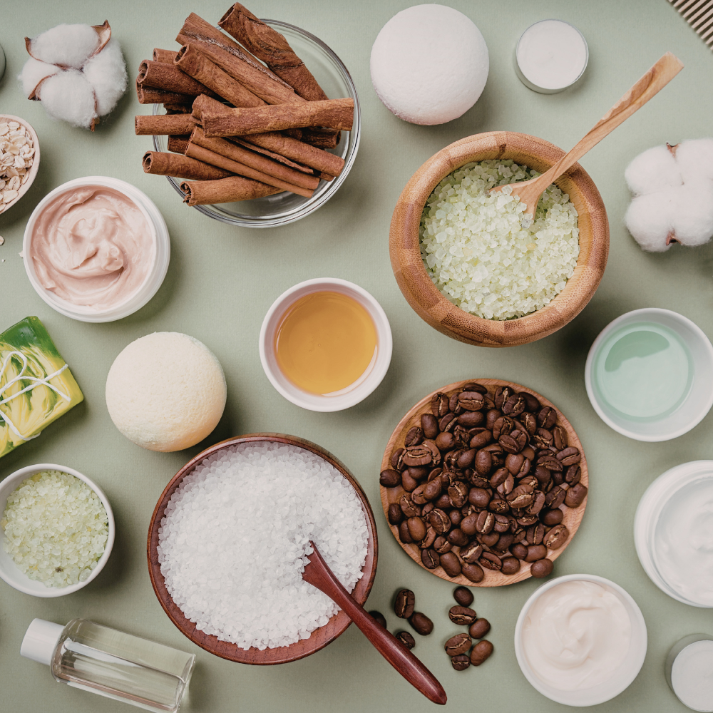 Ingredients for a DIY coffee scrub including coffee grounds, coconut oil, sugar, and honey.