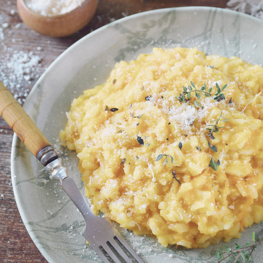 Creamy risotto spreading softly on a plate with grated Parmesan on top