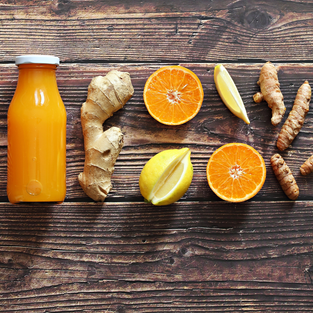 Ingredients for turmeric shots including fresh turmeric, ginger, orange, lemon, lime, and cayenne.