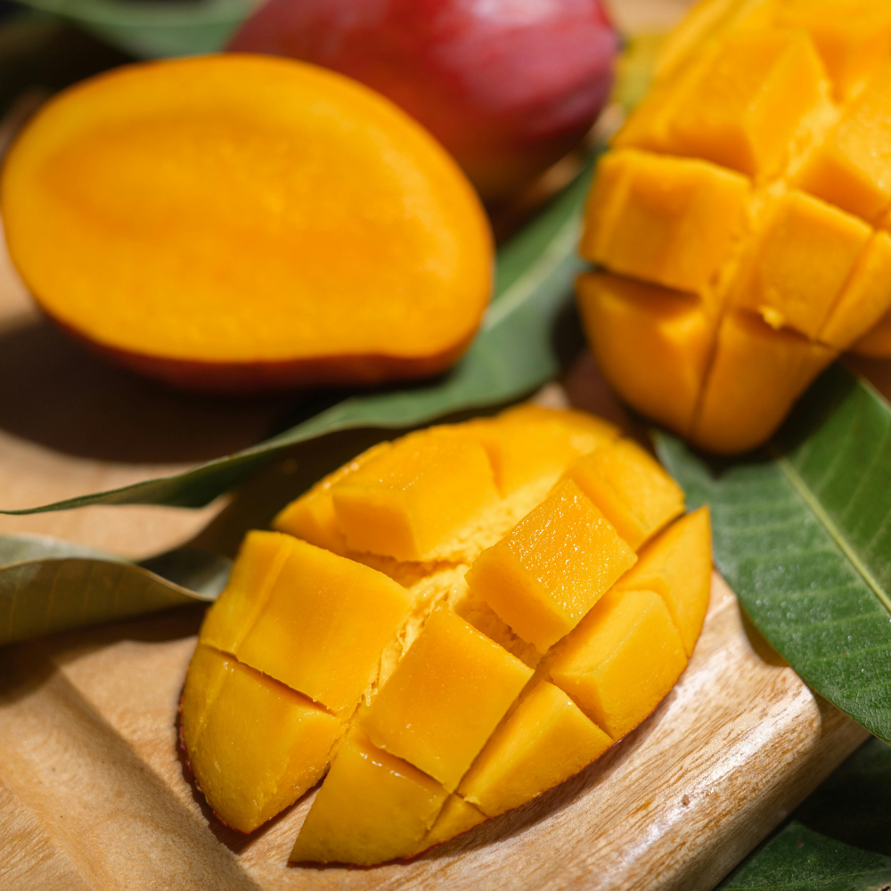 Fresh ripe mango sliced on a wooden cutting board for smoothie preparation.