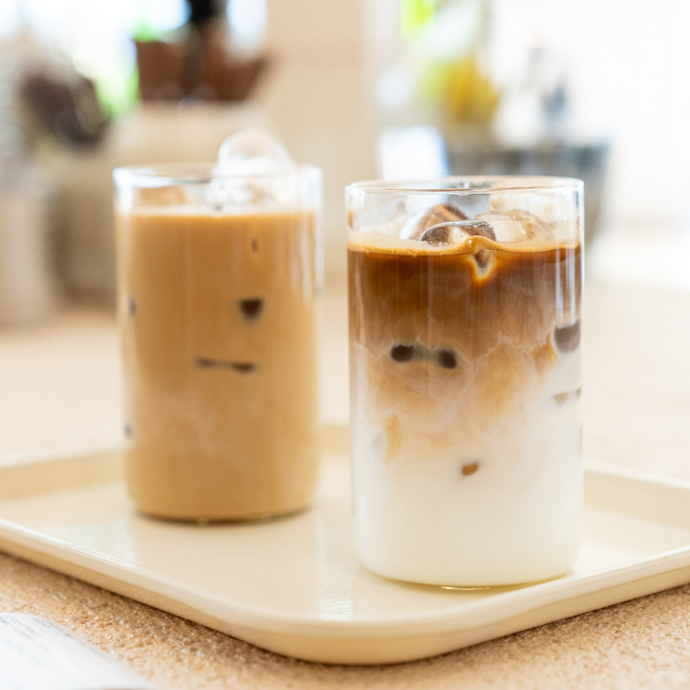 Refreshing iced coffee drinks in glass cups on a kitchen counter with milk, espresso, and layered coffee variations over ice