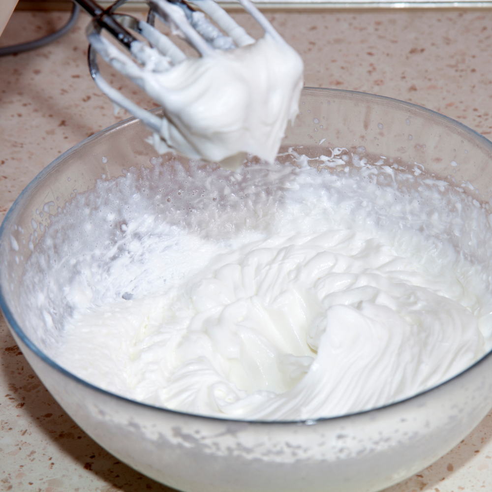 Stabilized whipped cream with stiff peaks for layered strawberry shortcake.
