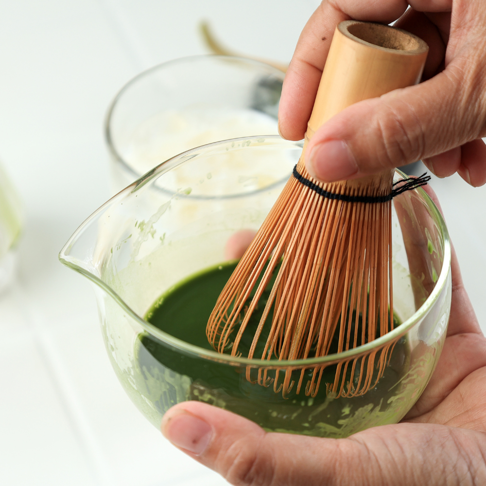 Matcha being whisked into hot water using a bamboo whisk