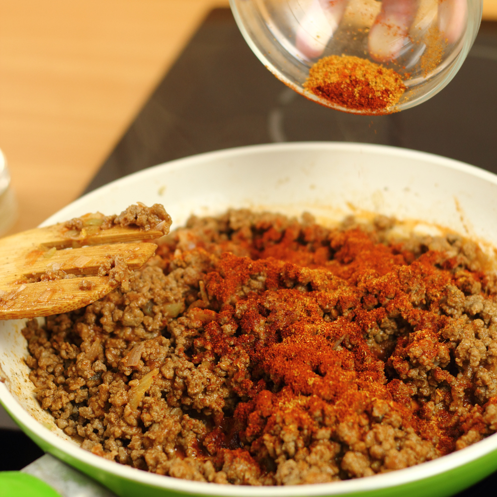 Ground beef cooking with onions and spices in a skillet for old-fashioned stuffed bell peppers
