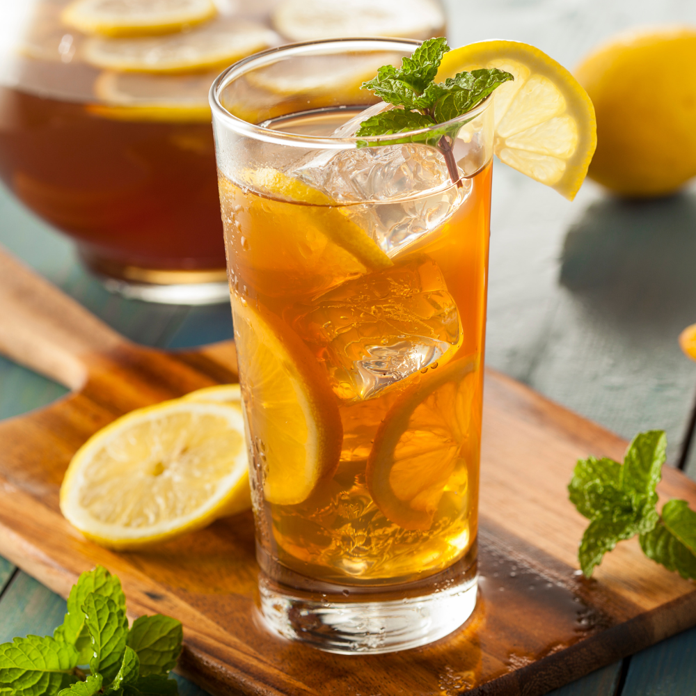 Refreshing mint and lemon balm iced tea with lemon slices served over ice on a summer afternoon.