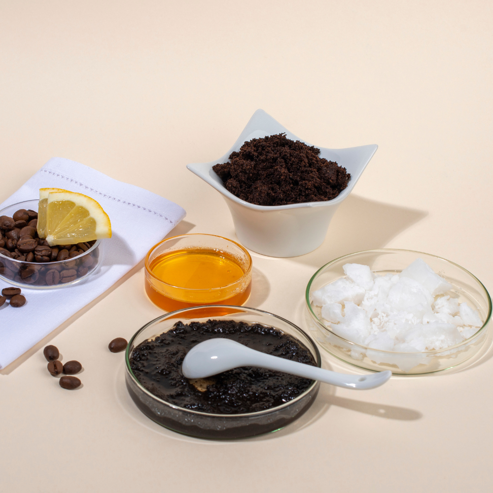 Natural ingredients for a DIY coffee scrub including coffee grounds, sugar, oil, and honey