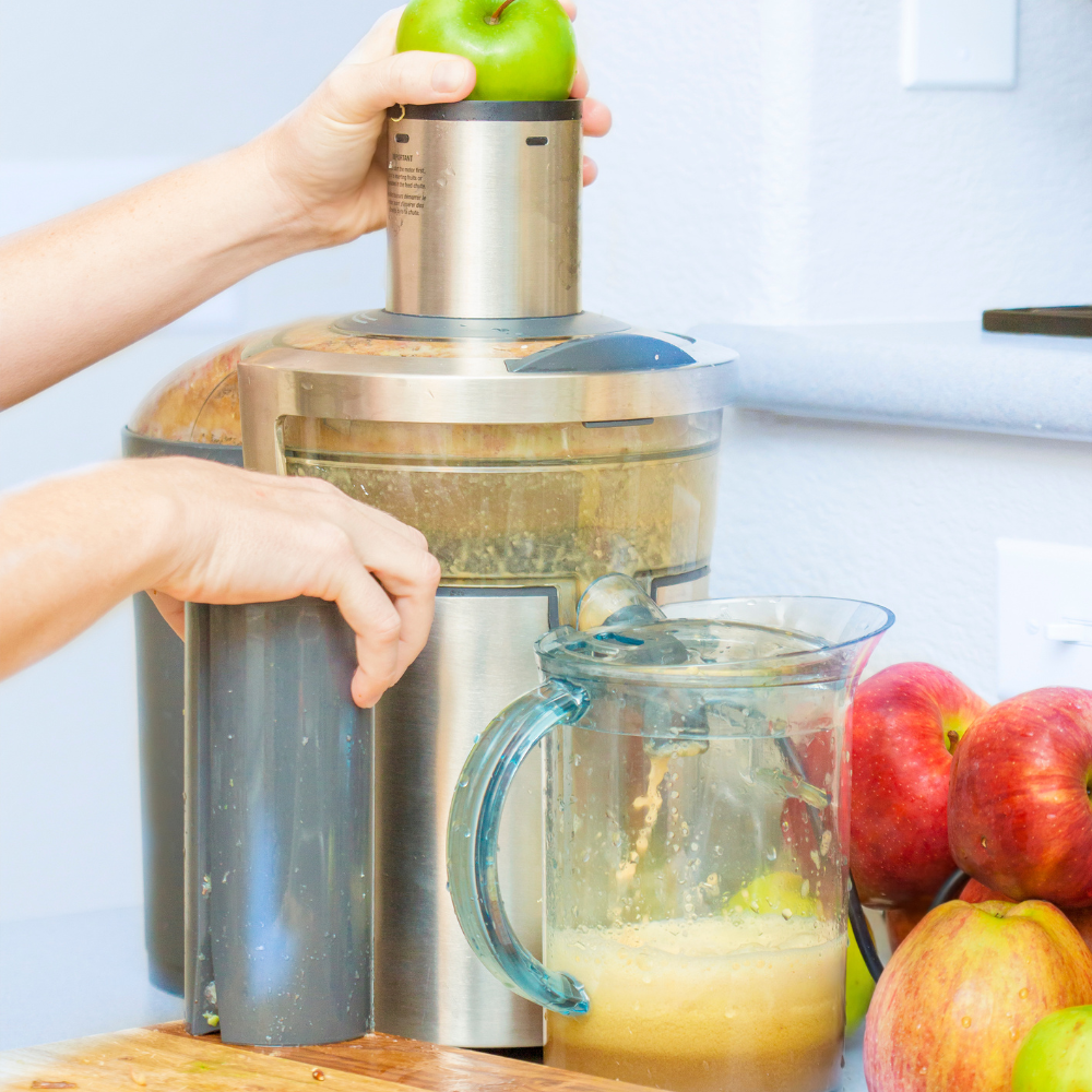 Making homemade ginger shots using a juicer with fresh ginger and citrus