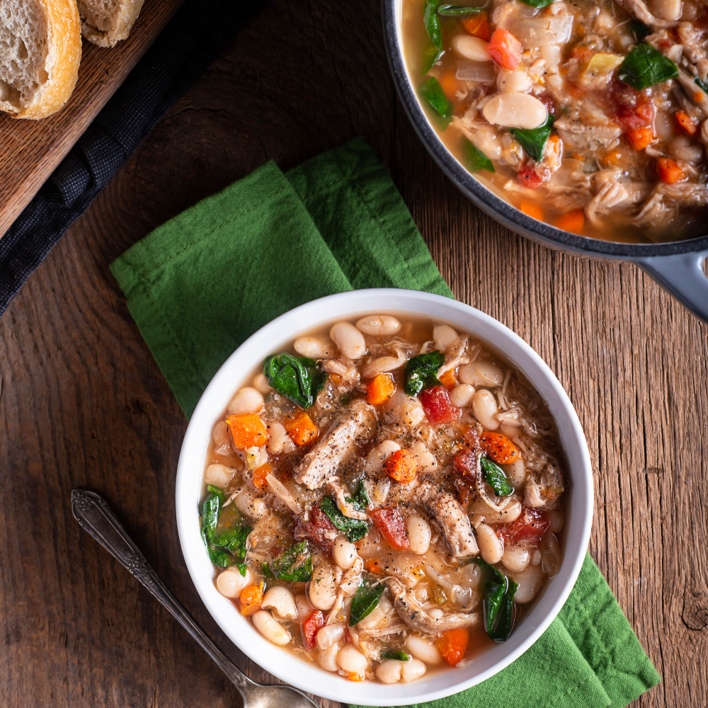 A steaming bowl of hearty ham and bean soup garnished with fresh parsley, showcasing a comforting and classic homemade recipe.