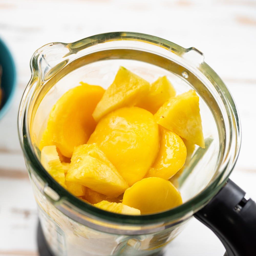 Mango smoothie blending into a smooth and creamy tropical drink inside a blender.