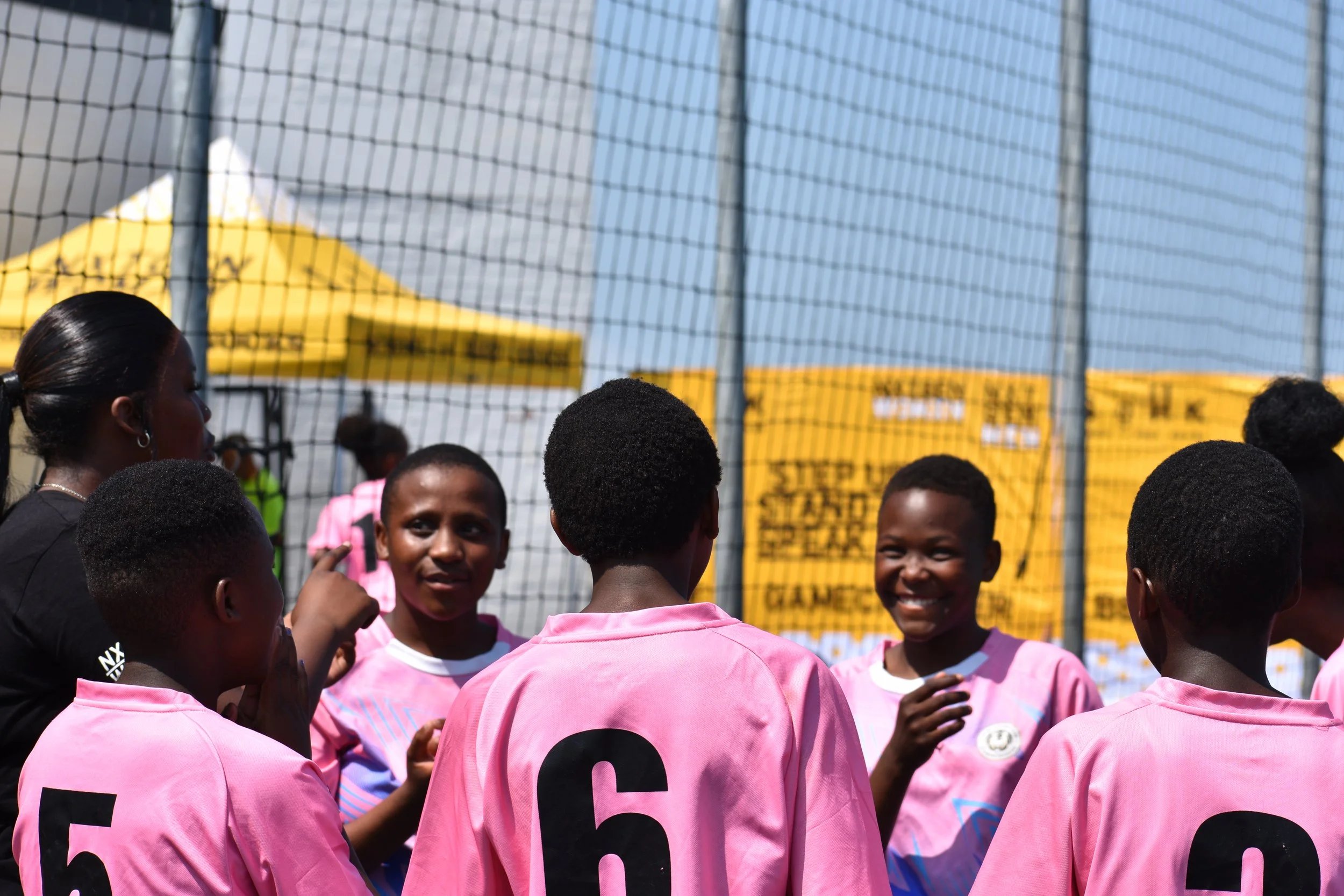  Group of girls and their coach talking in a soccer court.  