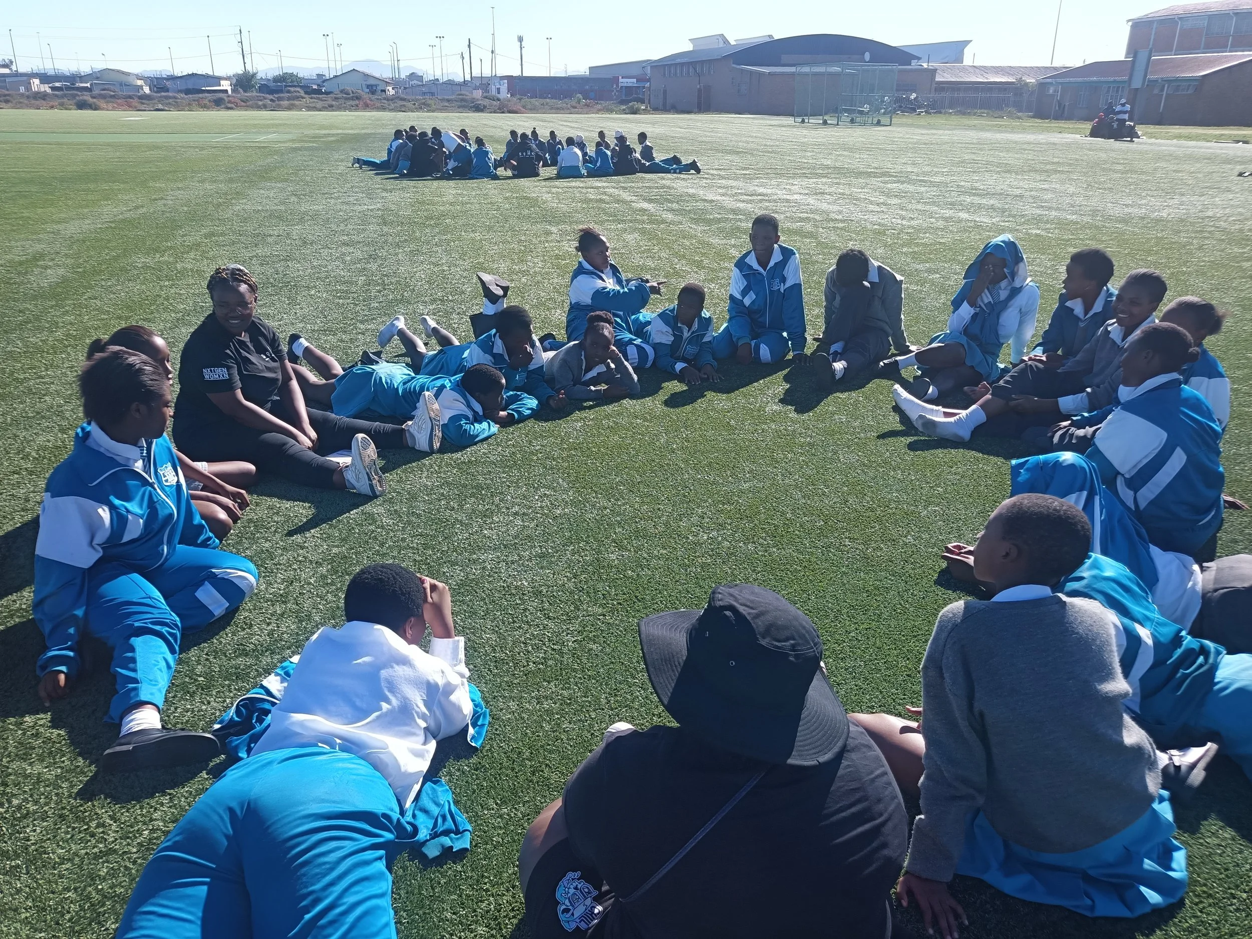  Participants sitting in a circle on the grass. 