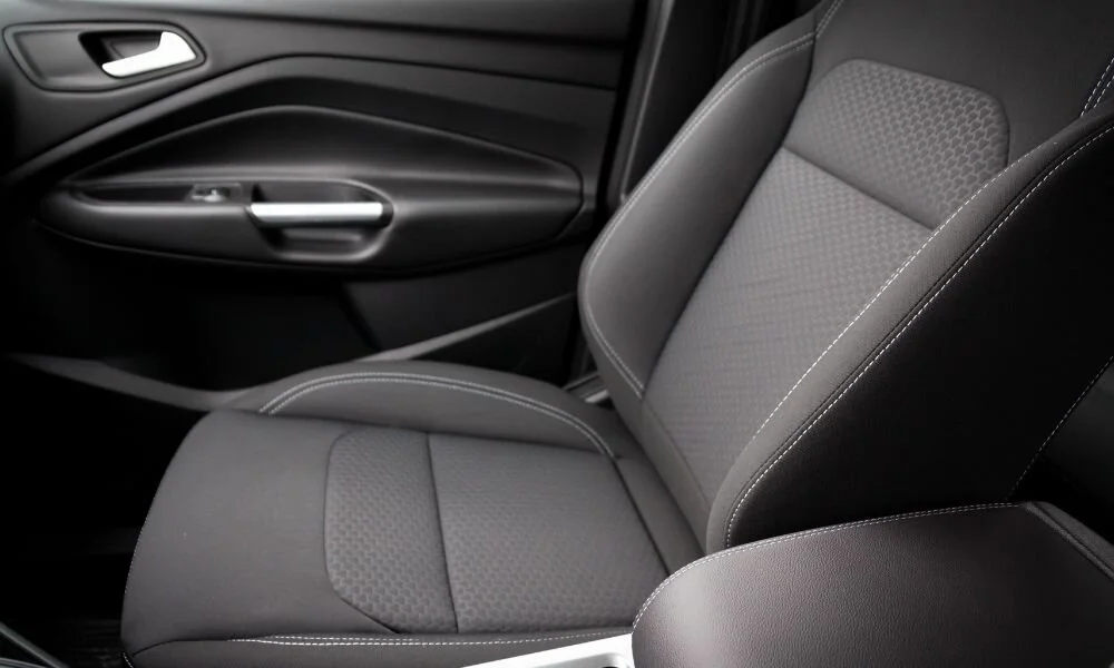 Car interior featuring a modern fabric seat with detailed stitching and a sleek door panel, emphasizing the importance of maintaining vehicle aesthetics and comfort.