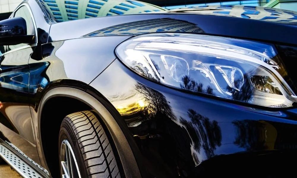 Black car exterior with shiny ceramic coating, showcasing reflective surface and detailed headlight design, highlighting benefits of ceramic coatings for vehicle protection.