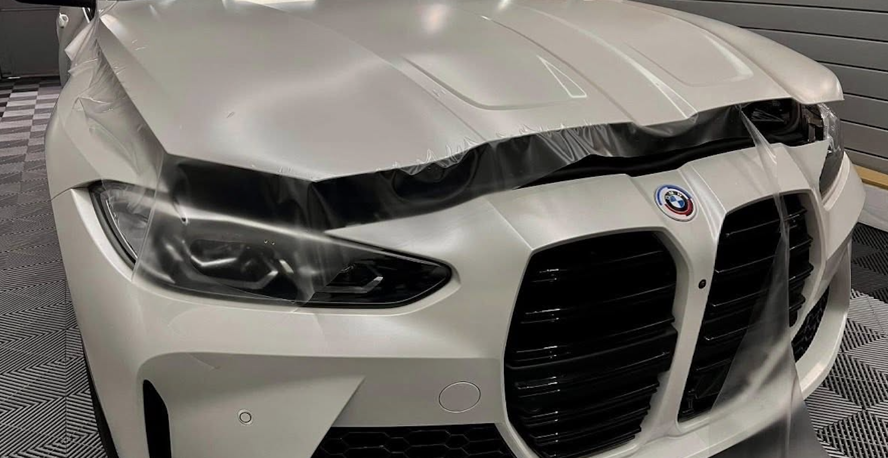 BMW vehicle with paint protection film partially applied on the hood and front bumper, showcasing installation process at Owners Pride in Omaha.