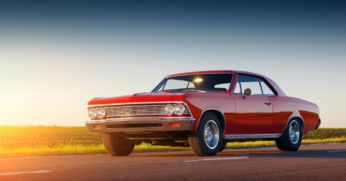 Classic red muscle car parked on a scenic road, showcasing vintage design and craftsmanship, relevant to classic car detailing and maintenance.