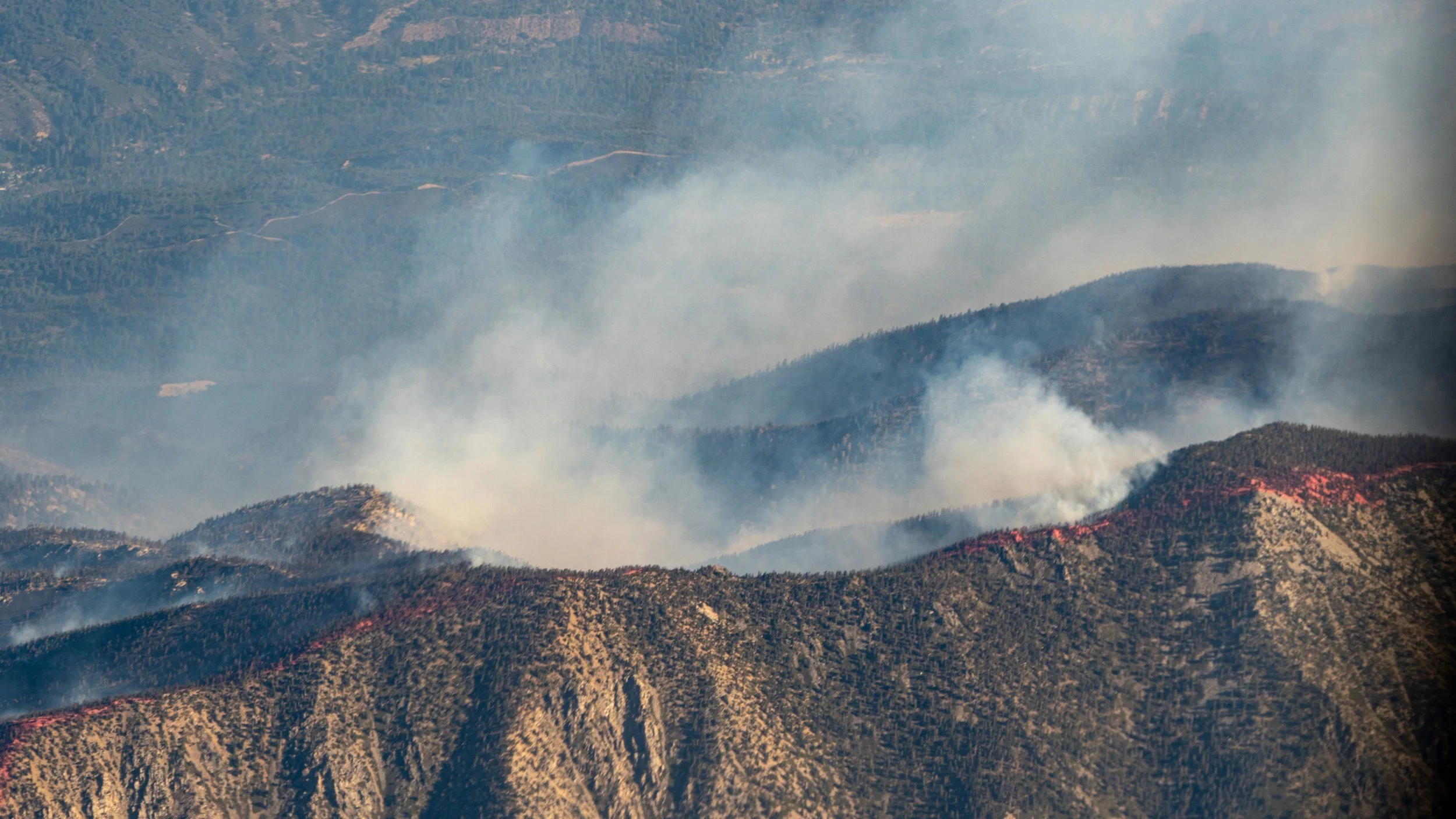 Mountains with smoke and flames from a wildfire.