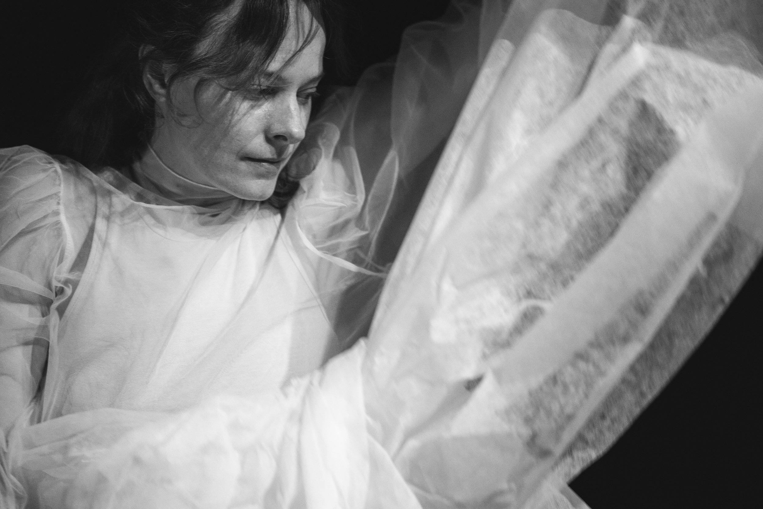 A woman lying in a coffin, resting her hand on her face.