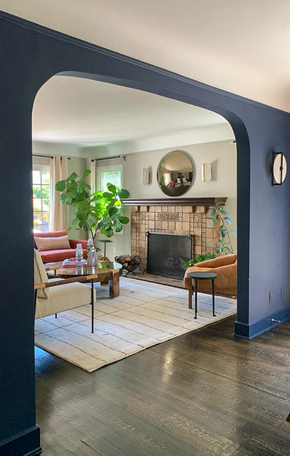 Hancock Park home living room and dining room with an eclectic modern furniture mix, featuring accent sconces over the original fireplace and flanking the dining room arched entryway.