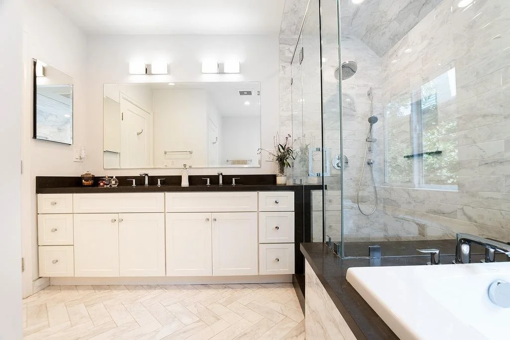 Los Angeles white and gray primary bathroom featuring a double vanity with lighting, a shower with frameless glass enclosure, and a drop-in bathtub with a quartz deck and tiled front