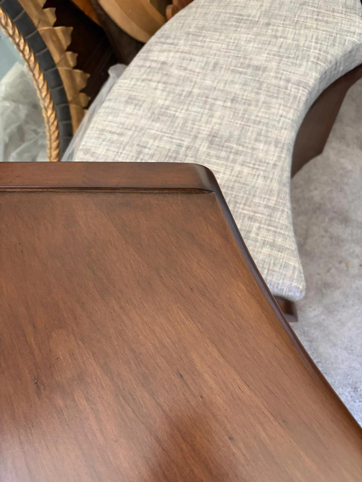 Close-up overhead view of the custom curved alder wood console tabletop and bench, featuring the finished walnut stain and custom upholstered performance fabric cushion.