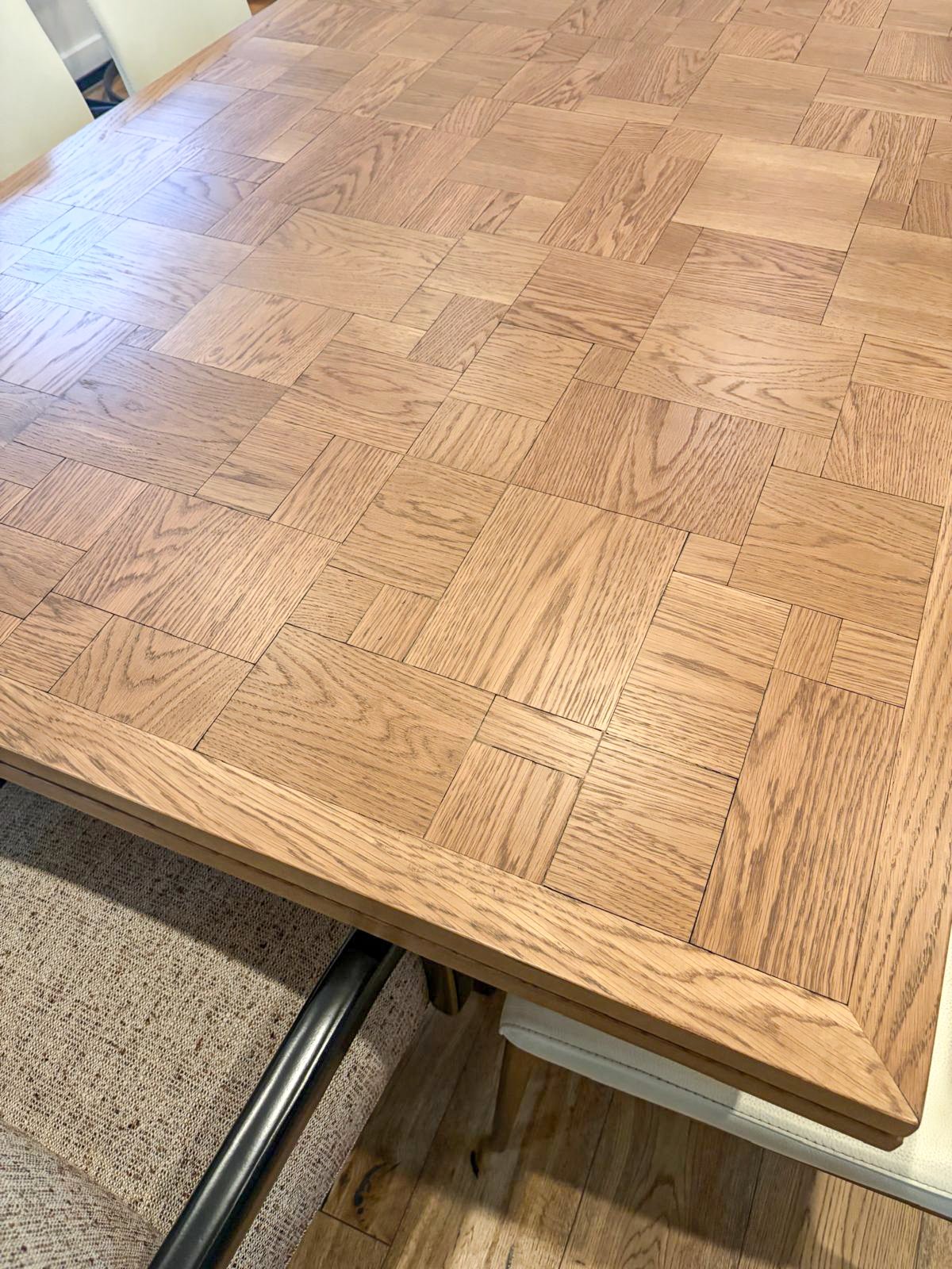Custom white oak dining table with parquet top in light walnut finish, leather ivory side chairs, and custom reupholstered head chair in performance fabric.