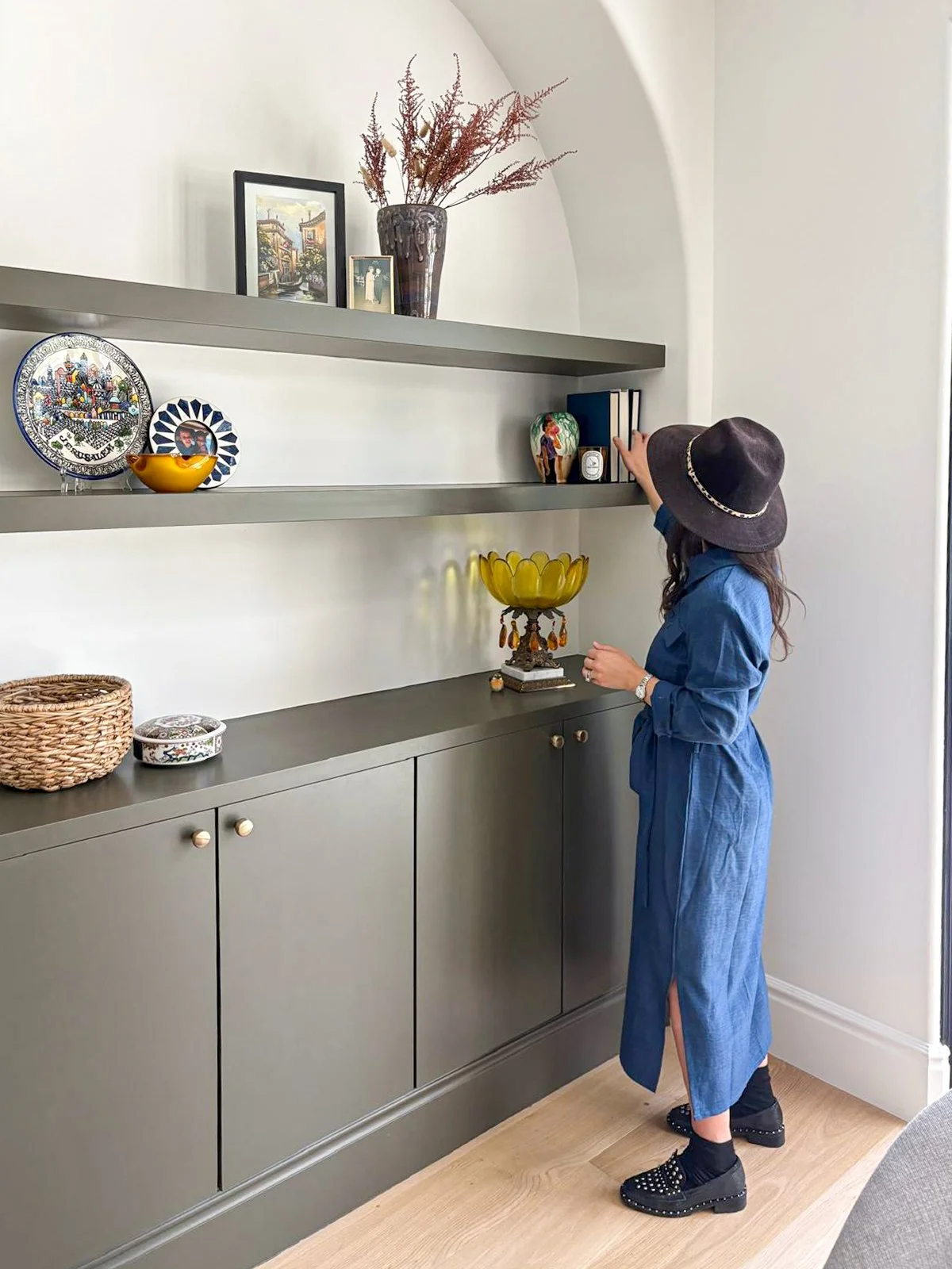 Interior designer styling arched niche shelving with green cabinetry in Beverlywood family room.