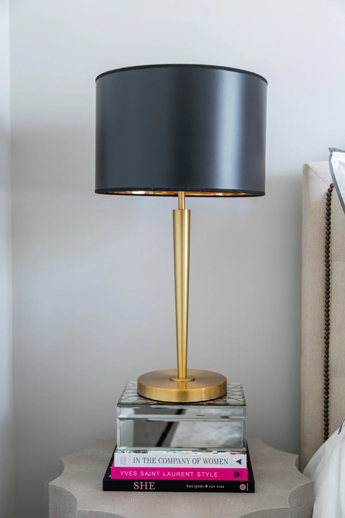 Concrete bedside table with black and brass table lamp sitting on a stack of books