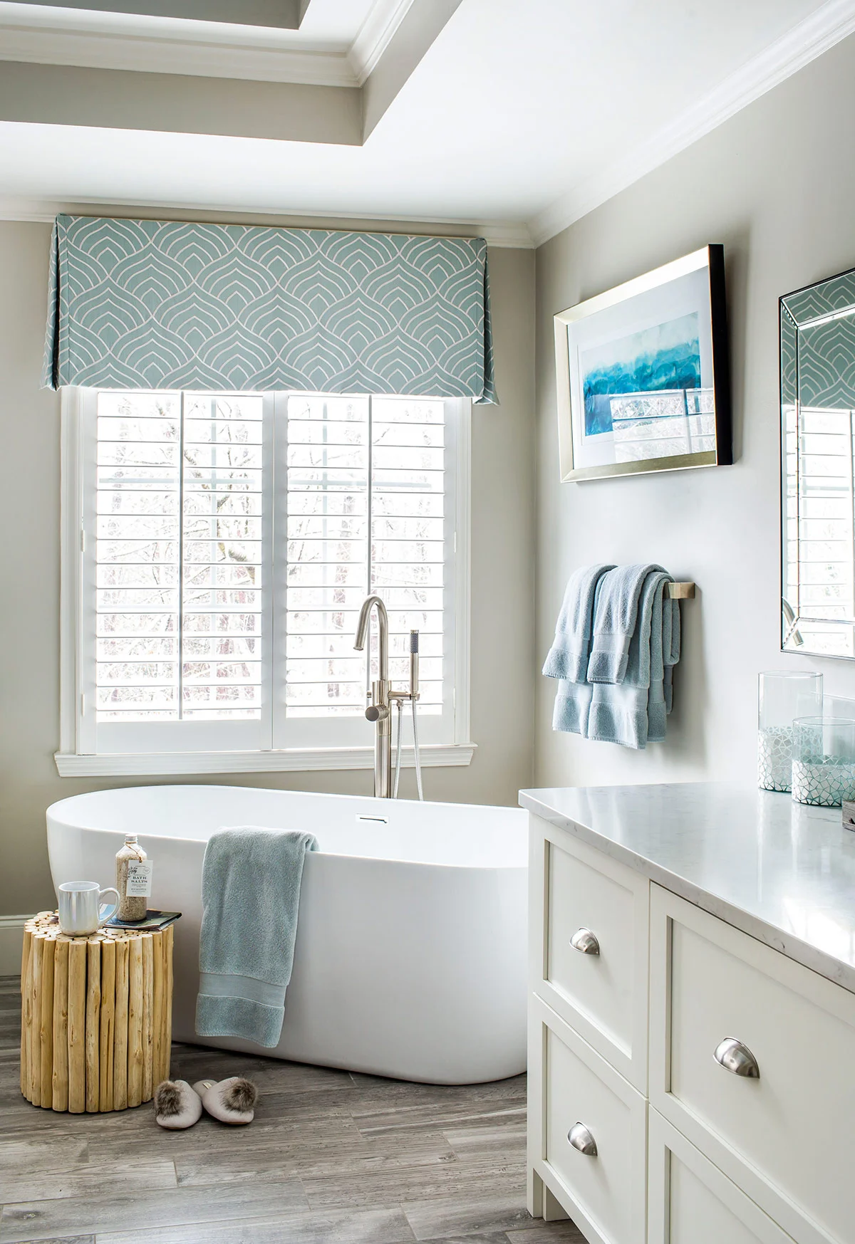 Fresh master bathroom, with wood-look tiles, free standing tub, and custom white cabinetry
