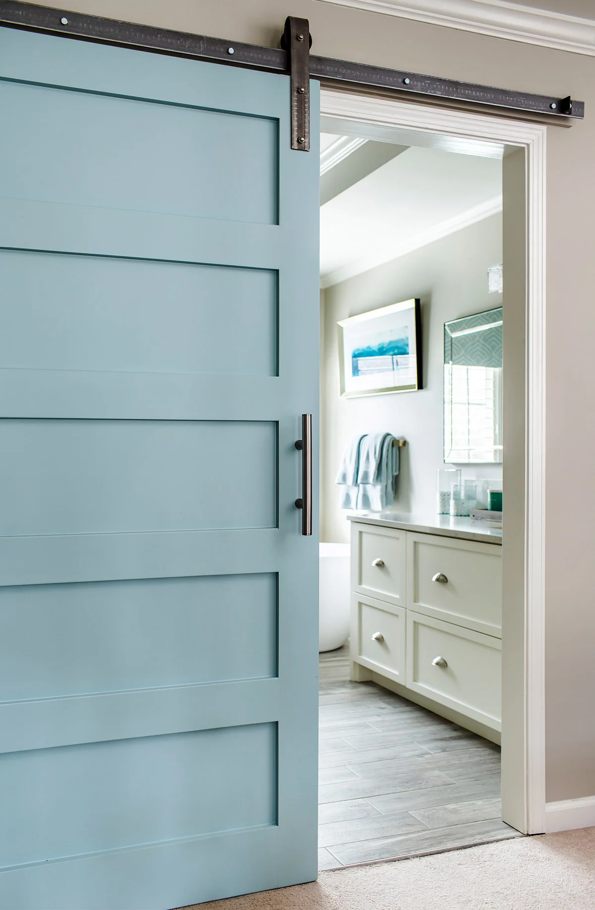 Sliding aqua blue barn door with steel track in master bathroom