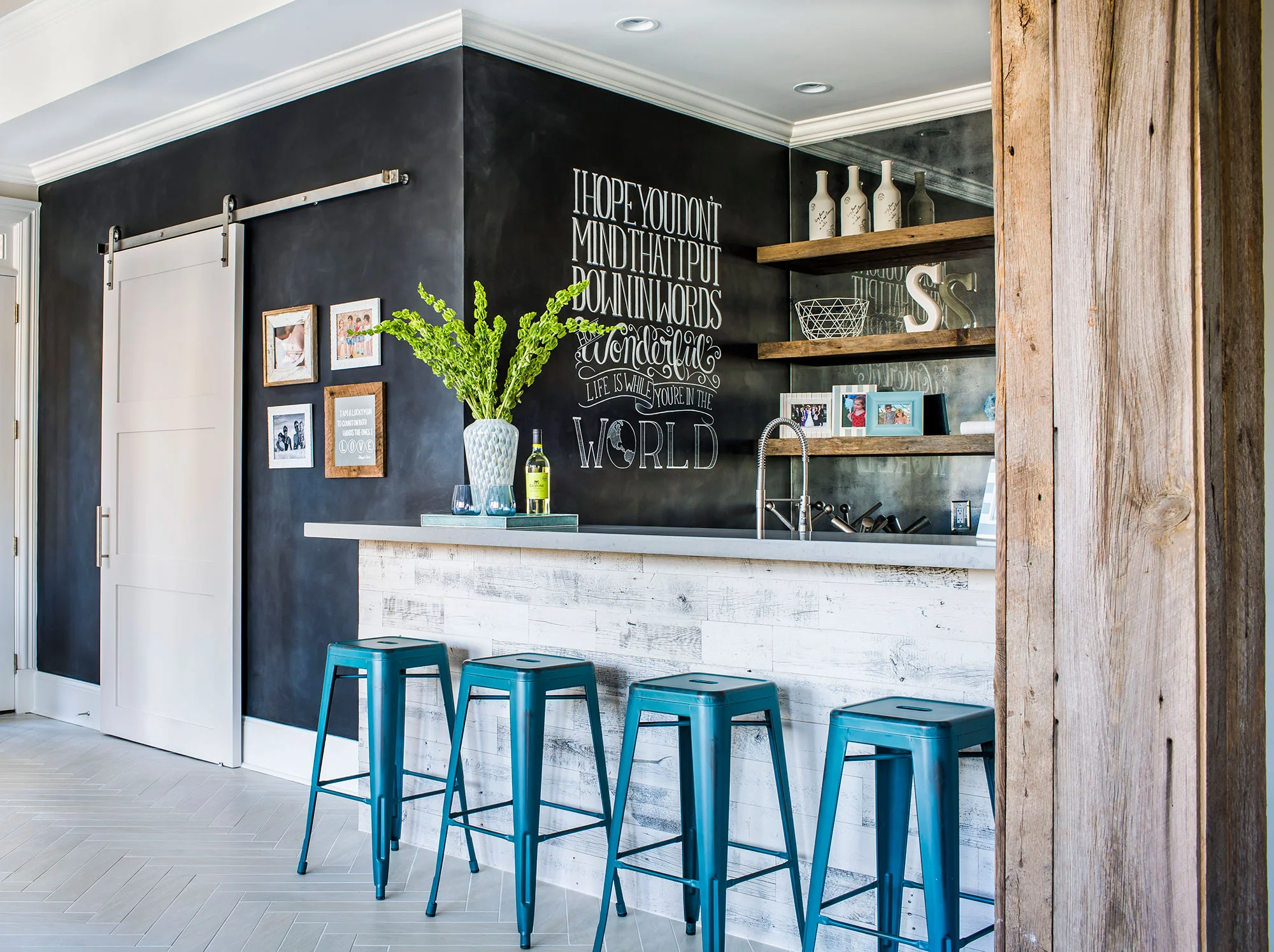 Basement wet bar featuring chalkboard walls, barn door, and floating shelves