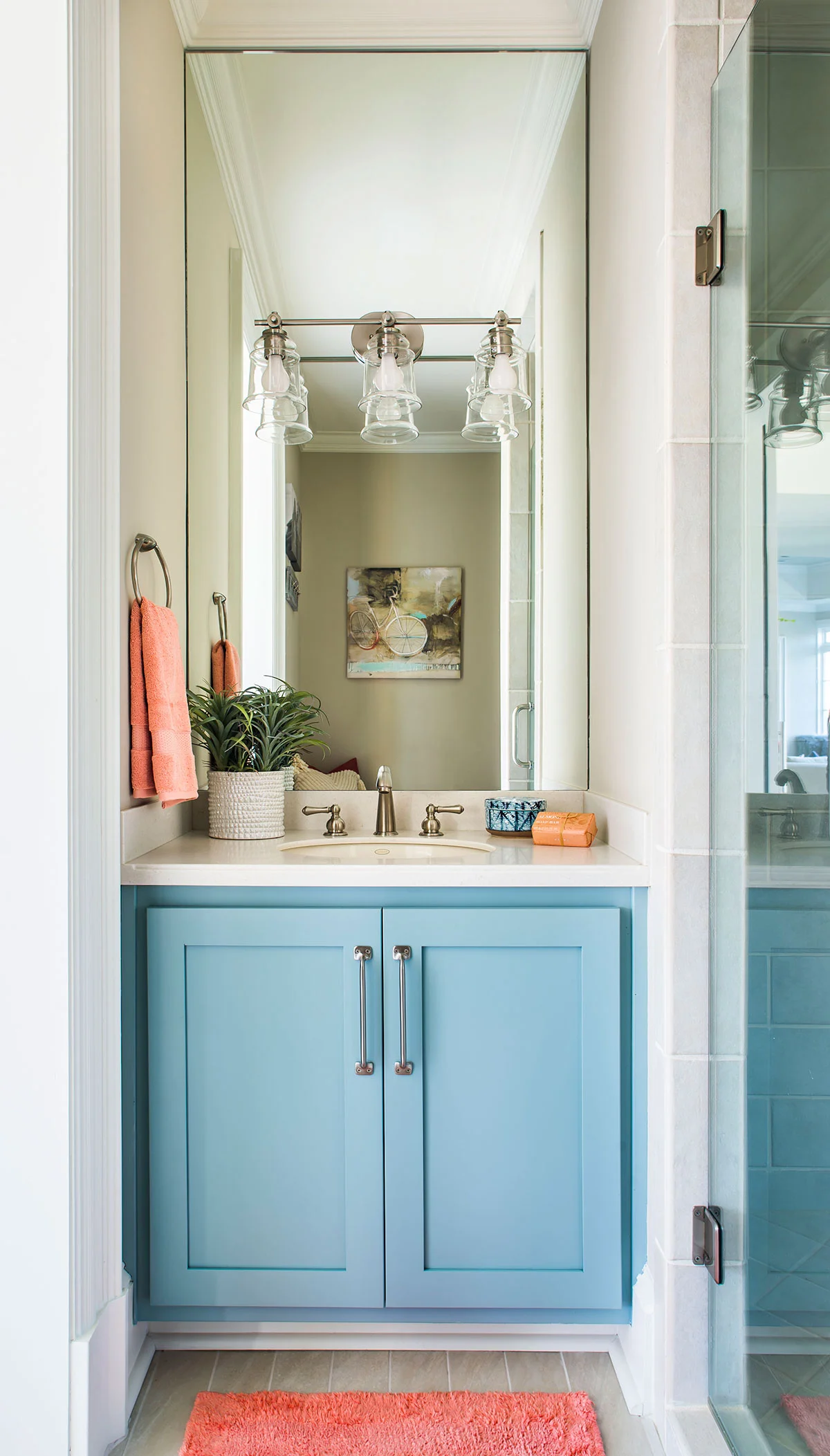 Colorful, coastal bathroom with turquoise cabinetry and brushed nickel hardware