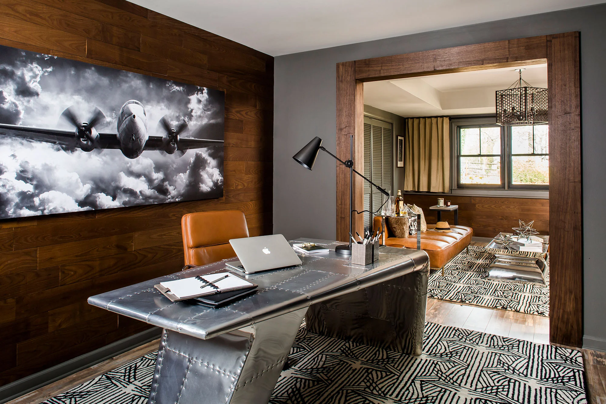 Masculine basement office with wood paneling, industrial desk, and leather accents.