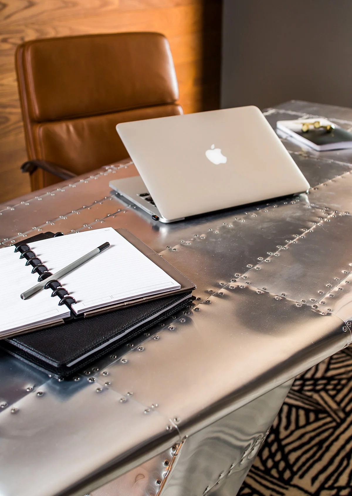 Industrial airplane wing desk and caramel leather chair in basement office