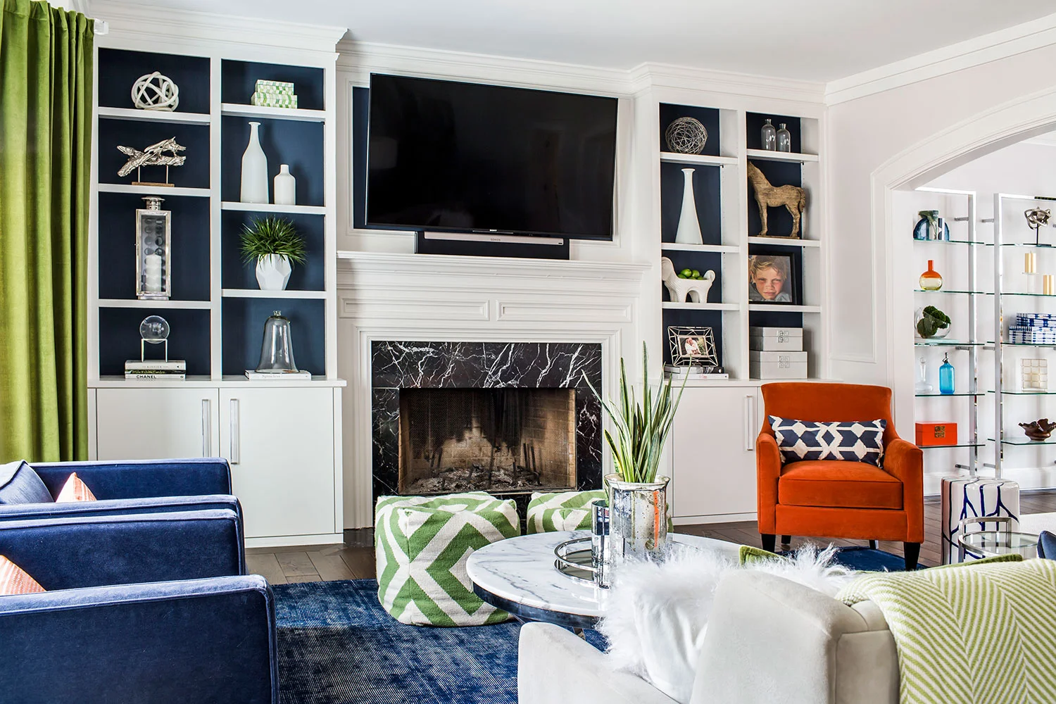 Living room with navy area rug, orange chair and a mix of midcentury modern and contemporary styling