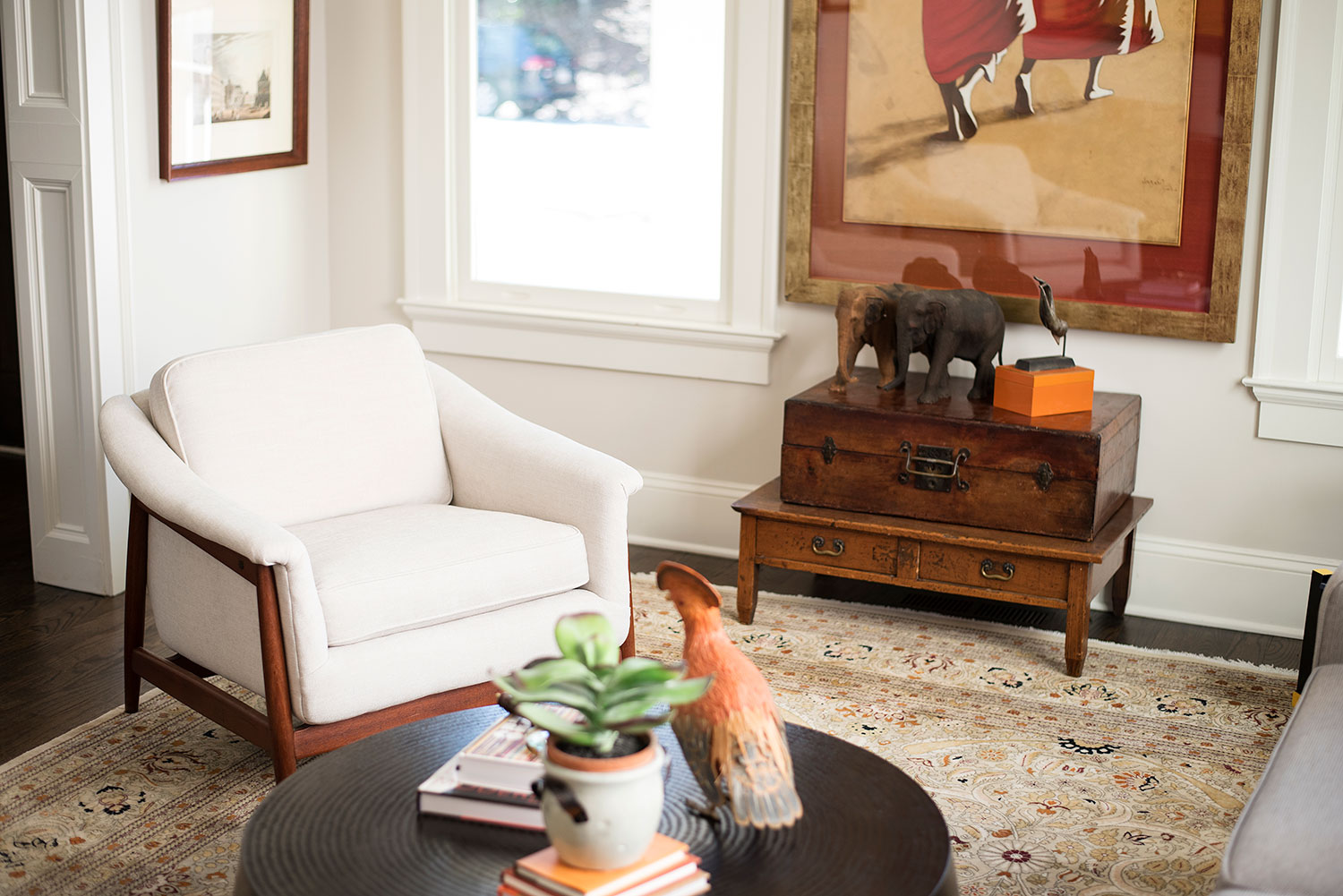 Transitional sitting room with ivory arm chair, beige area rug, and rich wood furniture