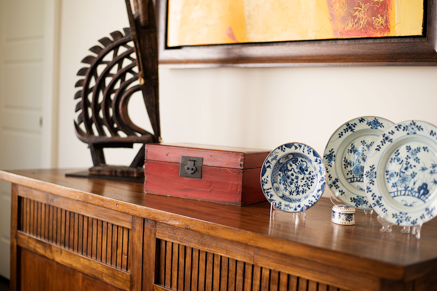 Wood sideboard displaying antelope sculpture and china plates